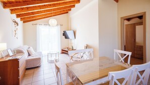 Una habitación acogedora con techo de madera, una cama, un televisor, una mesa de comedor y un televisor en la pared.