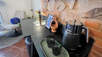 A modern kitchen with a stone wall, a flat-screen TV, a coffee maker, and a small dining table.