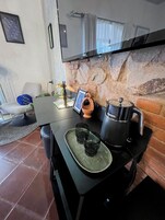 A modern kitchen with a stone wall, a flat-screen TV, a coffee maker, and a small dining table.