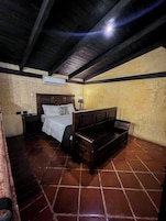 Un dormitorio con cama, mesita de noche, lámpara y un equipo de aire acondicionado.