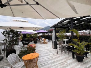Eine Außenpatio-Terrasse mit Tischen, Stühlen, Sonnenschirmen und Blumentöpfen.