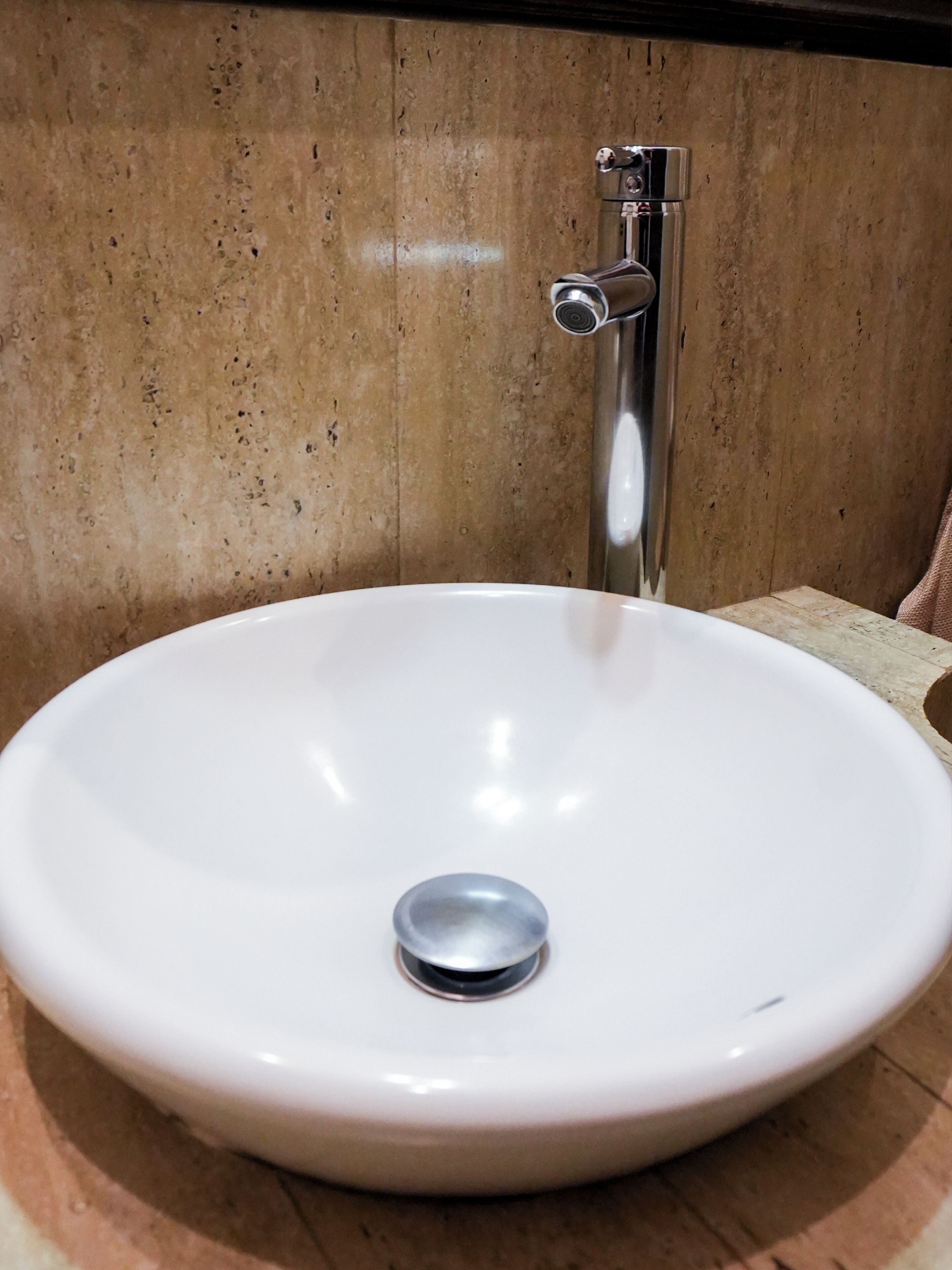 Un lavabo de cerámica blanca con un grifo cromado montado sobre una pared con diseño moteado.