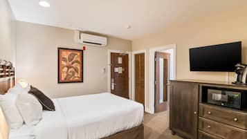 Ein Hotelzimmer mit Bett, Fernseher, Mikrowelle, Kleiderschrank und Klimaanlage.