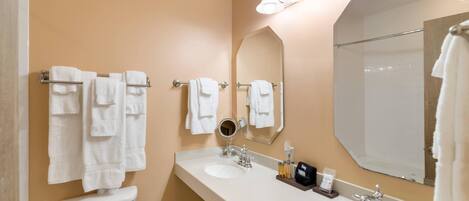 A bathroom with two sinks, a toilet, a large mirror, and multiple towels.