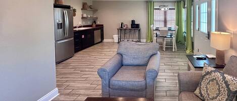 A living room with a sofa, a coffee table, and a dining area with a table and chairs.