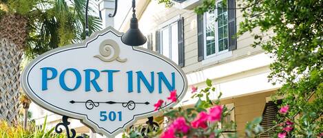 A sign for Port Inn with the number 501, surrounded by greenery and a building in the background.