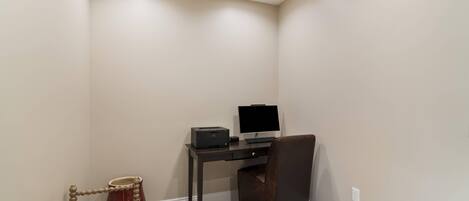A corner room with a desk, chair, and a small table.