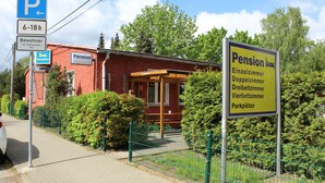 A building with a sign indicating it is a pension with single, double, and triple rooms, and parking available. - Pension Schwalbenweg (Schoenefeld)