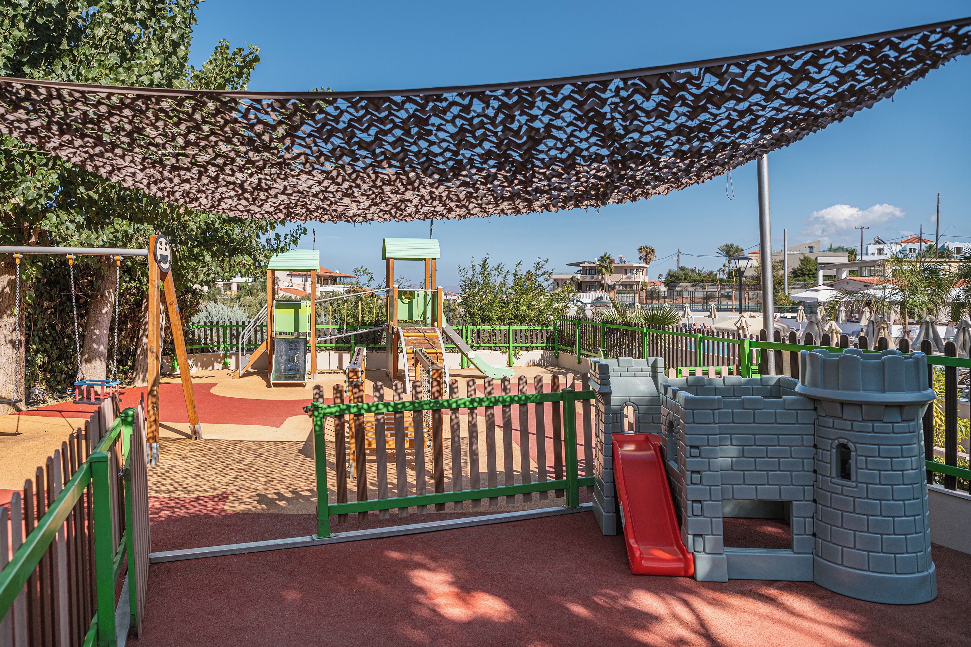 Un parque infantil con tobogán, estructuras para escalar y una casita con forma de castillo.