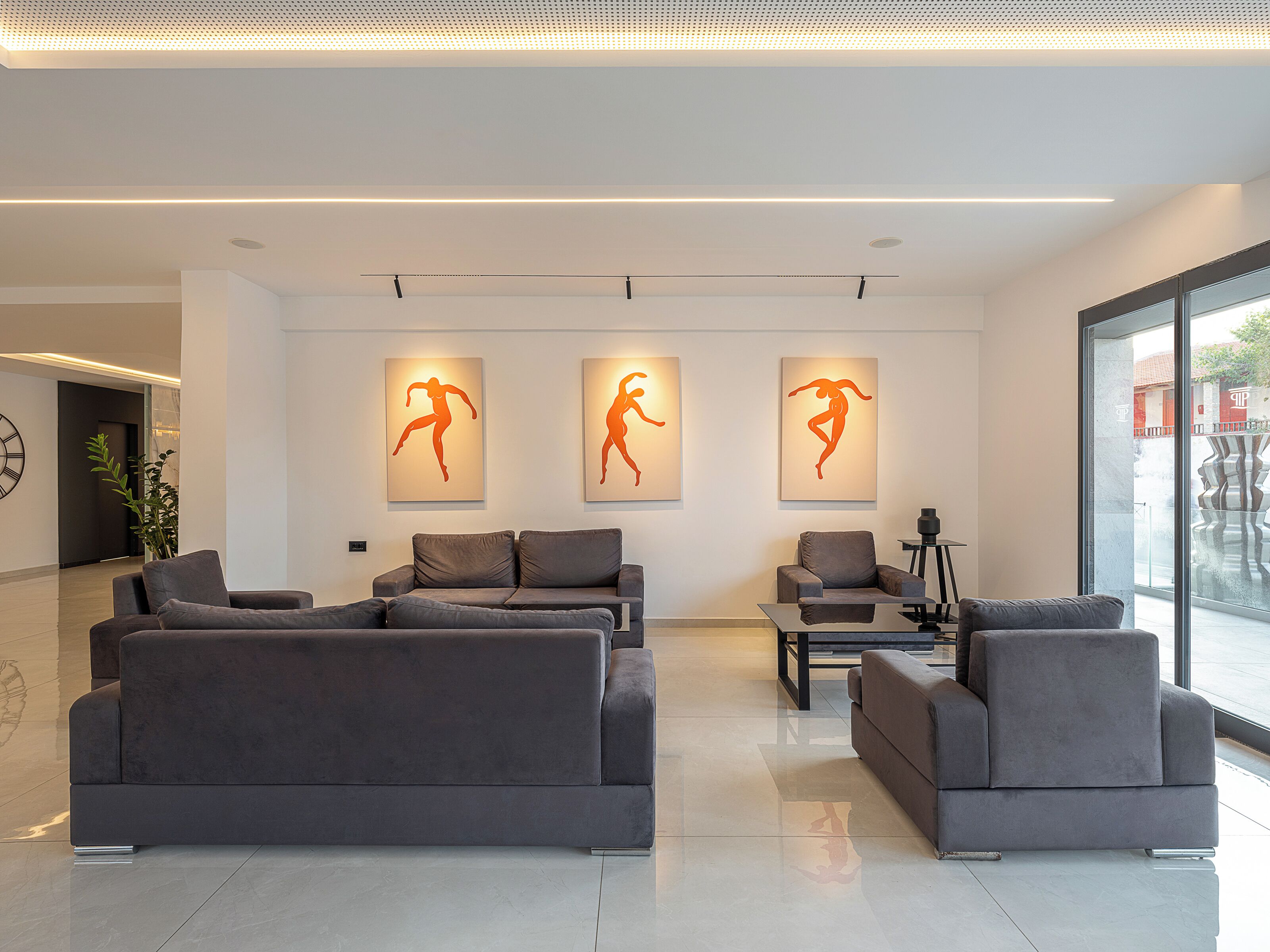 A modern living room with grey sofas, a coffee table, and wall-mounted artwork.