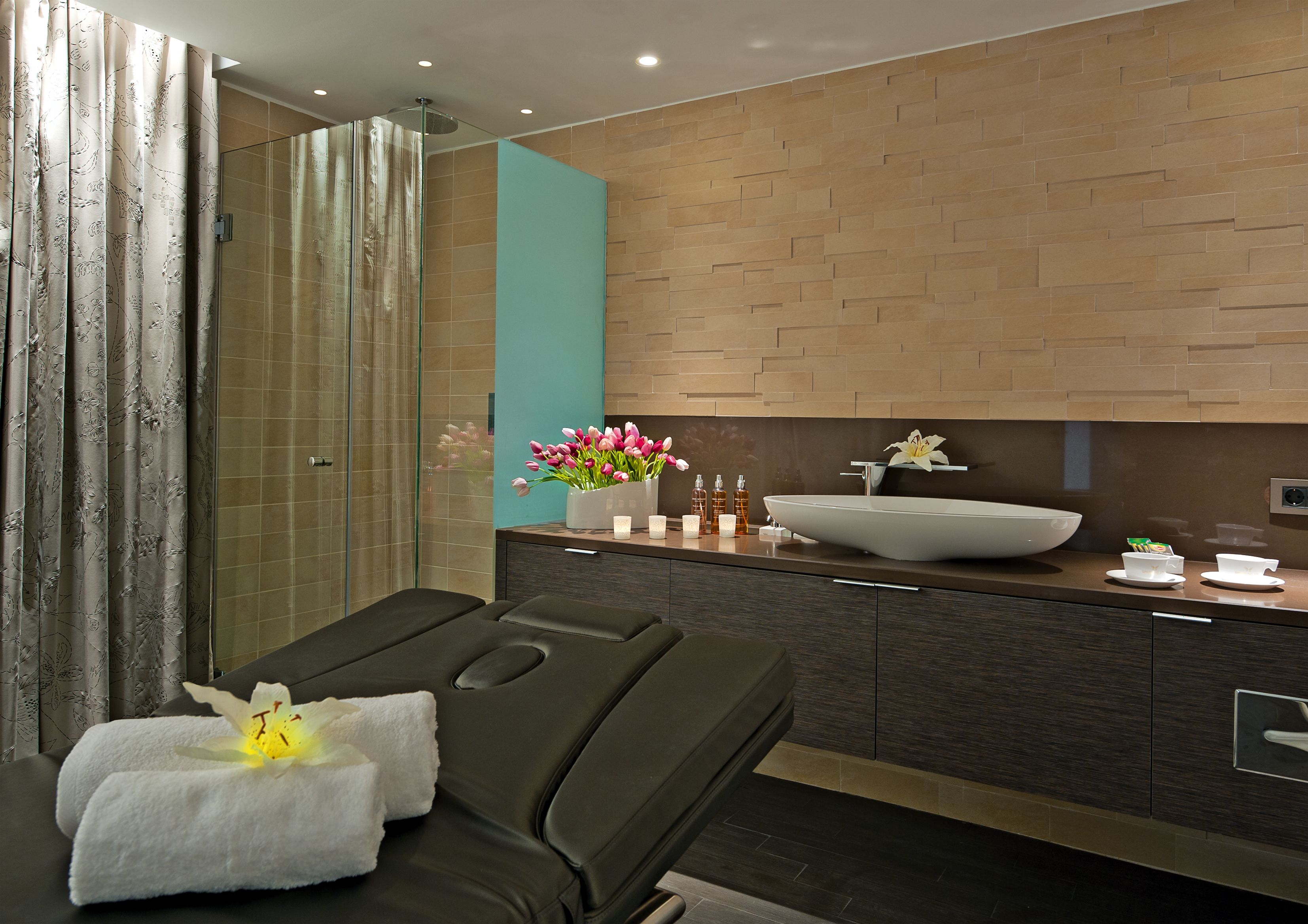 Un baño moderno con ducha de vidrio, lavamanos grande y sillón de masaje.
