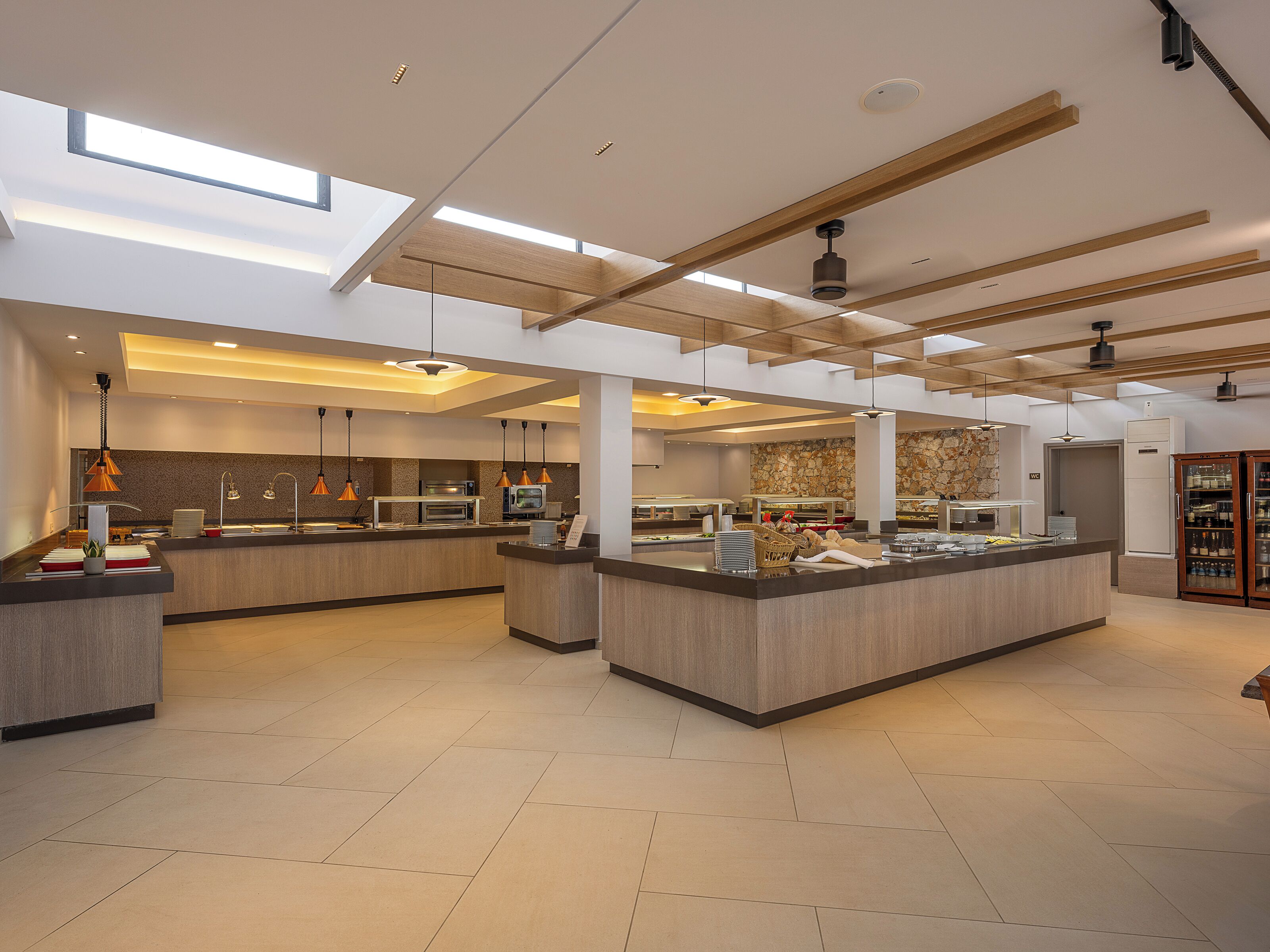 Cocina moderna con isla central, iluminación colgante y salpicadero de piedra.
