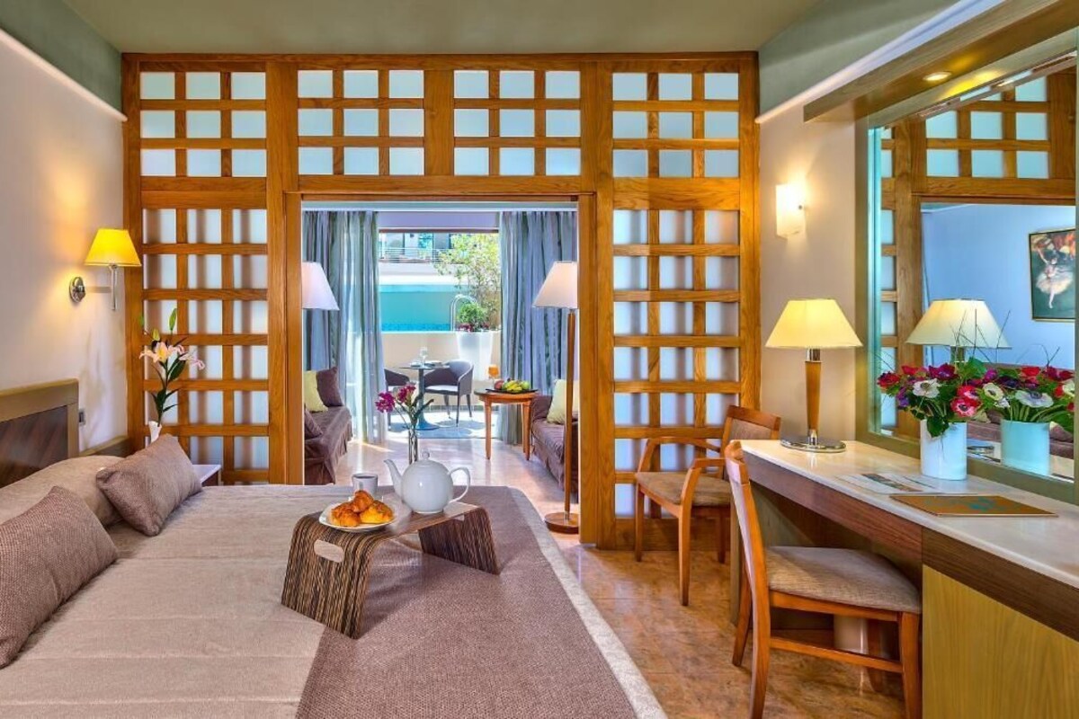 Habitación de hotel con cama, mesita de noche, escritorio y vistas al exterior.