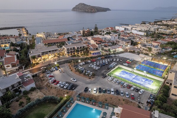 Vista aérea de un pueblo costero con un puerto deportivo, un estacionamiento amplio y una piscina.