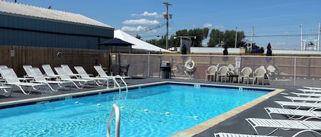 Una piscina con sillas de descanso y un área cercada.