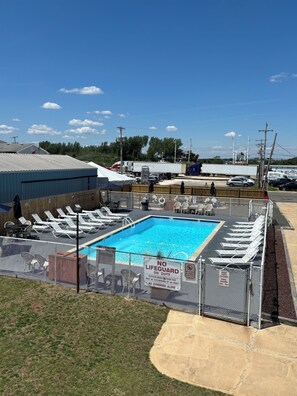 A swimming pool with sun loungers, a fenced area, and a sign indicating no lifeguard on duty. - Shore Point Motel (Point Pleasant Beach)