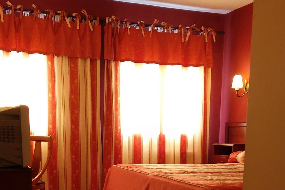 Ein Hotelzimmer mit einem Bett, einem Schreibtisch, einem Sessel und einem Fernseher.
