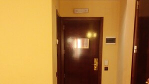 A hotel hallway with a closed door, a bench, and a television on a wooden stand. - Hotel Puerta De Javalambre (La Puebla de Valverde)