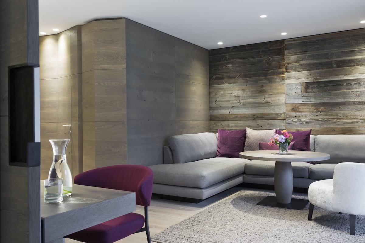 Un salon moderne avec un canapé gris, une table basse ronde et un fauteuil rouge.
