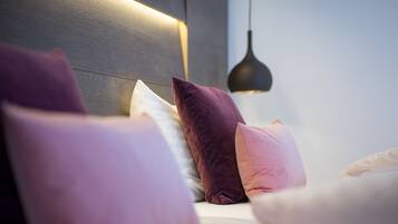 A bedroom with a wooden headboard, multiple pillows, and a pendant light.