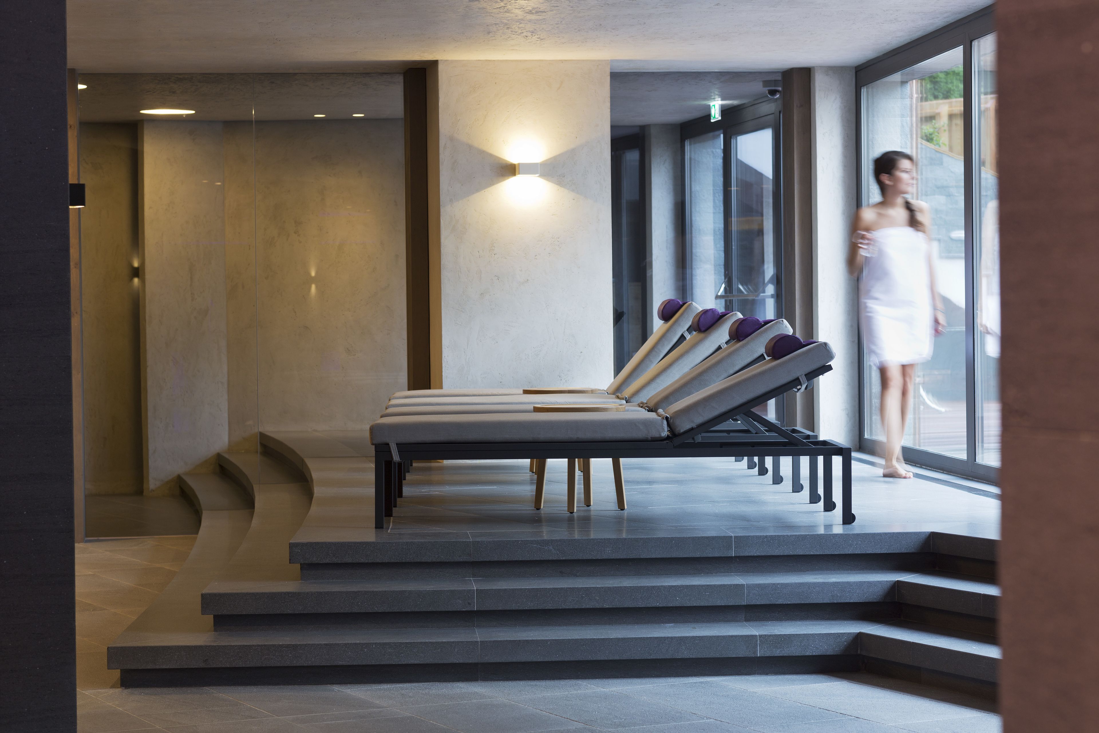 Un área de spa moderna con sillones reclinables y una pared de vidrio.