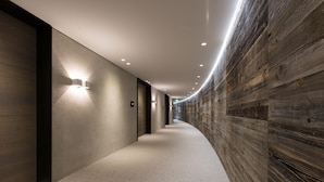 Een hal met een gebogen plafond, ingebouwde verlichting en een houten wand aan één kant.