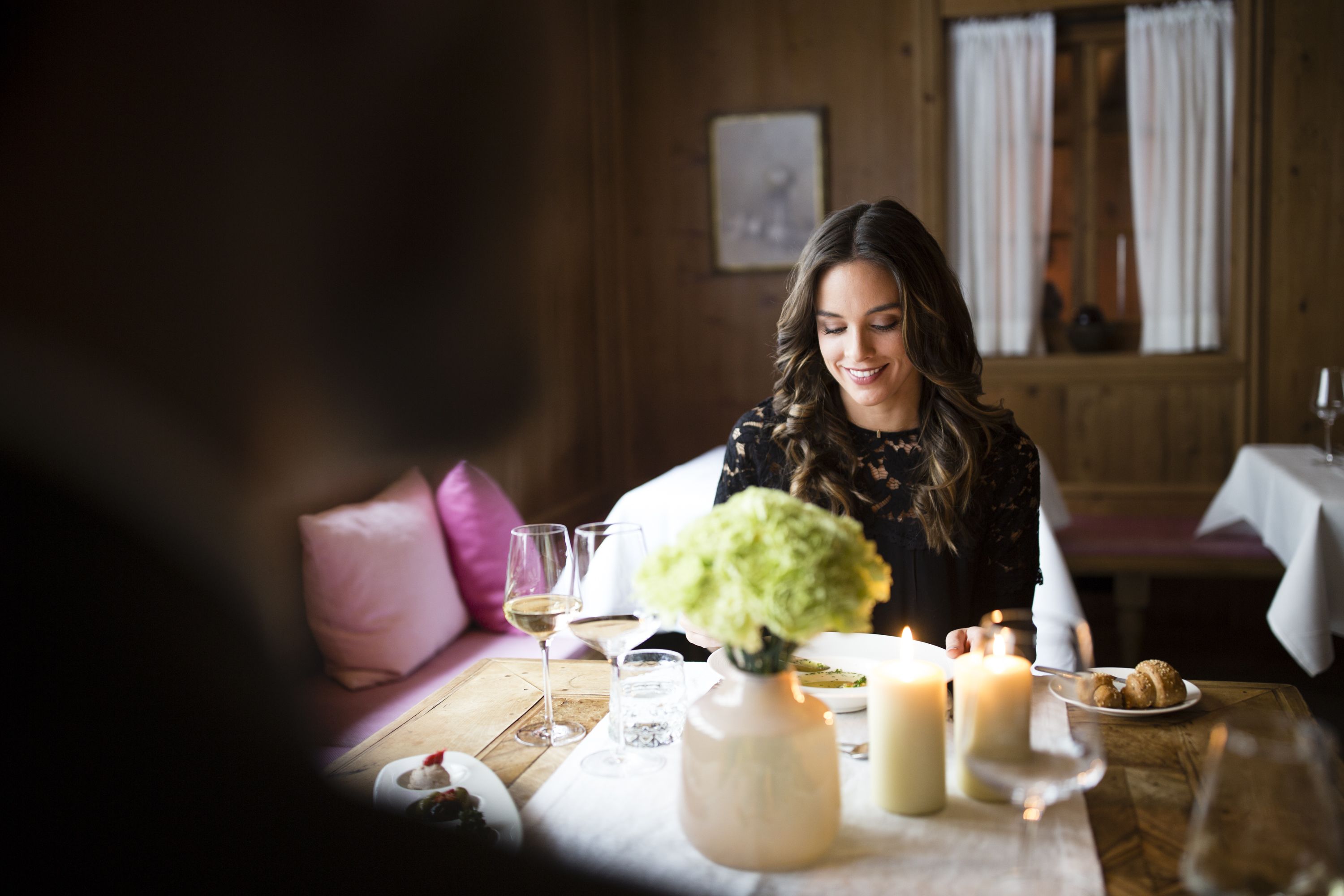 A dining table with candles, glasses, and a vase with flowers.