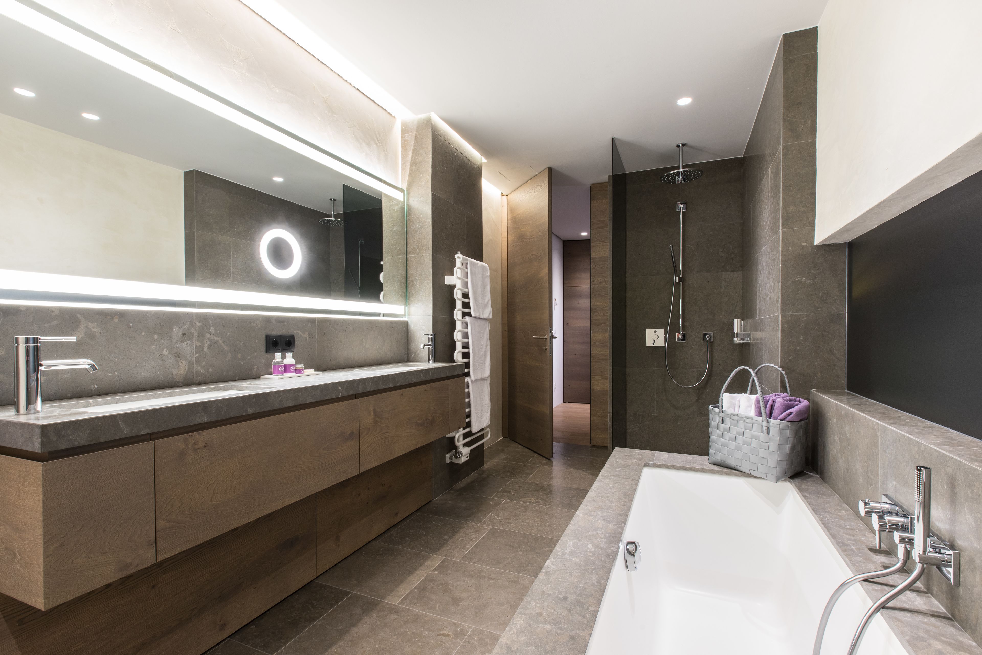 Un baño moderno con un espejo grande, una bañera, una ducha y un tocador con toallero.