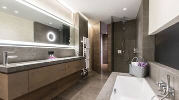 Un baño moderno con un espejo grande, una bañera, una ducha y un tocador con toallero.