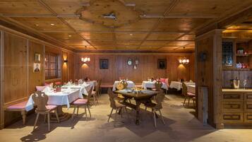 A dining area with wooden walls, multiple tables, and chairs.