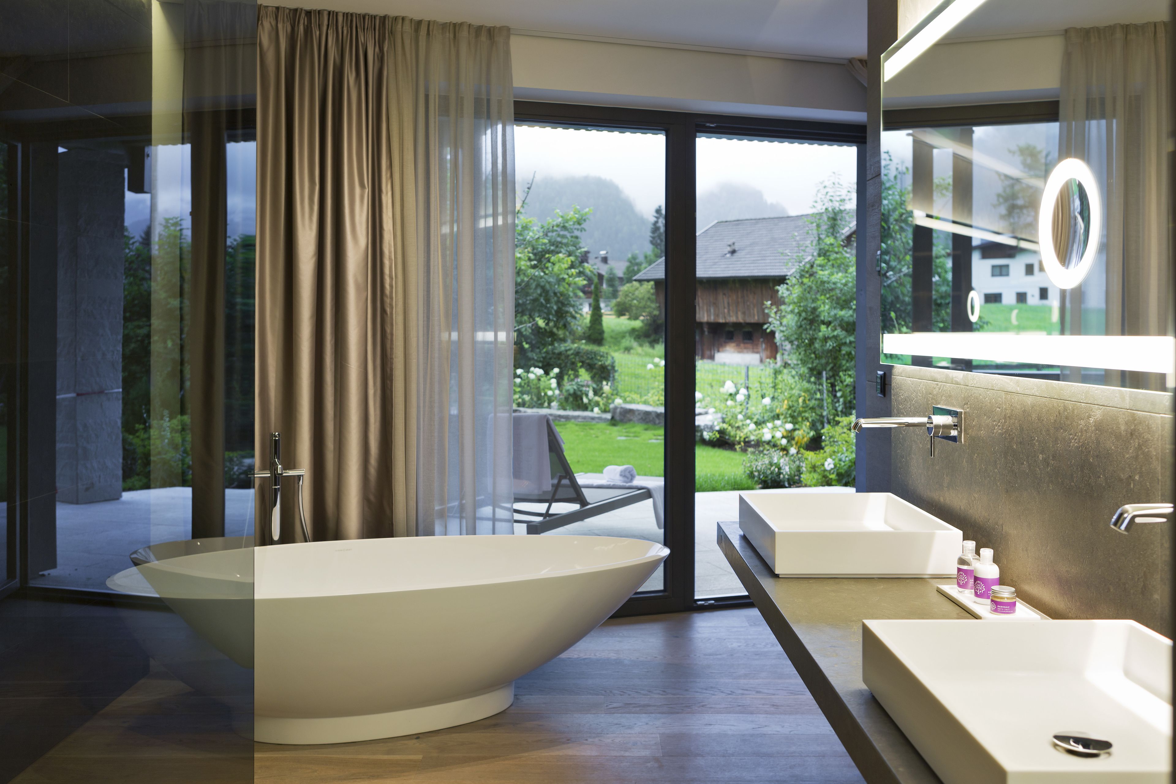 A modern bathroom with a large freestanding bathtub, a double sink vanity, and a large mirror.