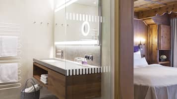 A modern bathroom with a large mirror, wooden vanity, and a bed with a white bedspread.