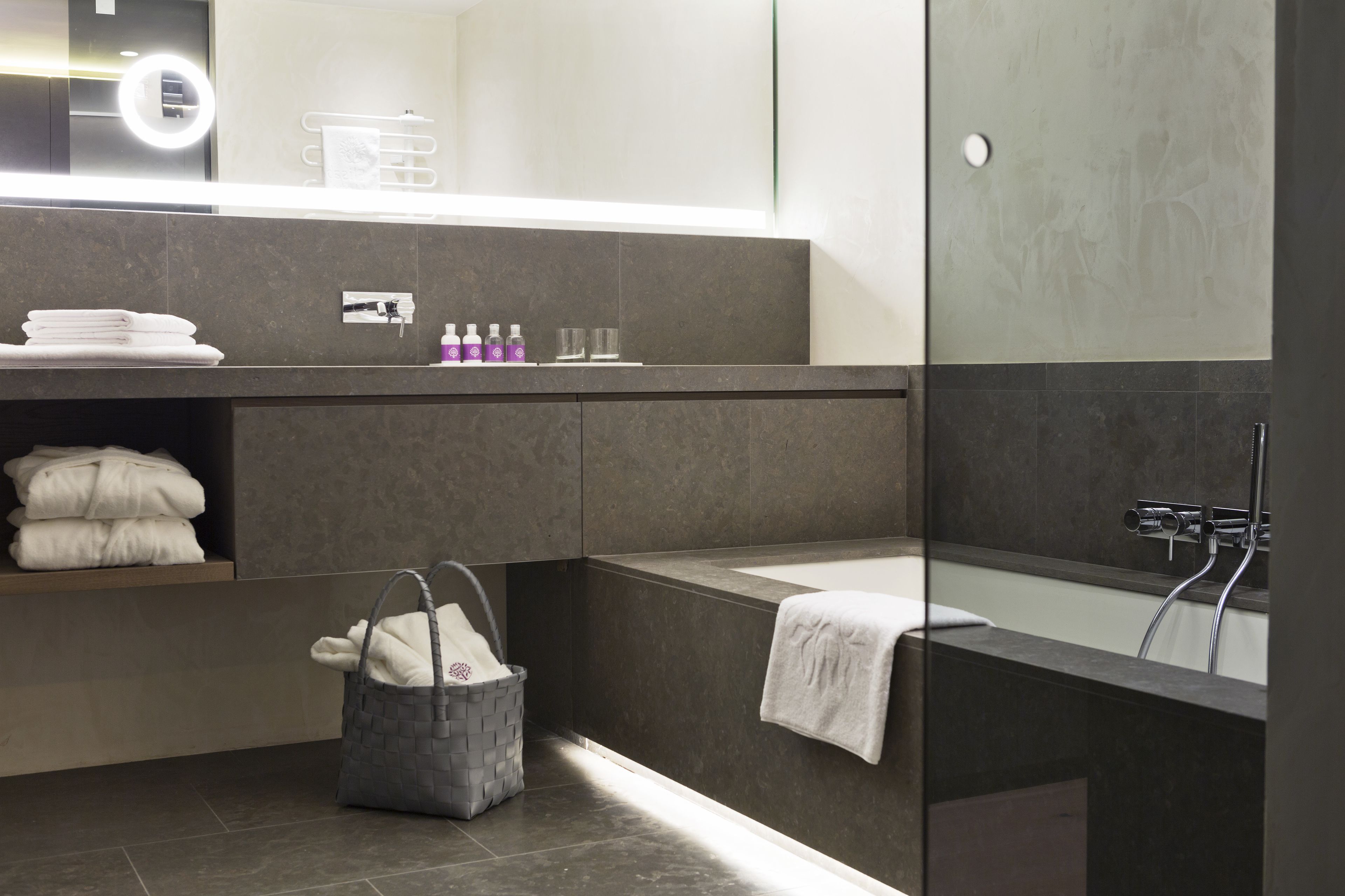 Un baño moderno con una bañera grande, una ducha con mampara de vidrio y un lavabo con espejo.
