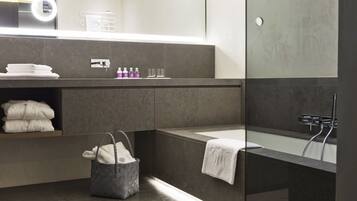 Un baño moderno con una bañera grande, una ducha con mampara de vidrio y un lavabo con espejo.