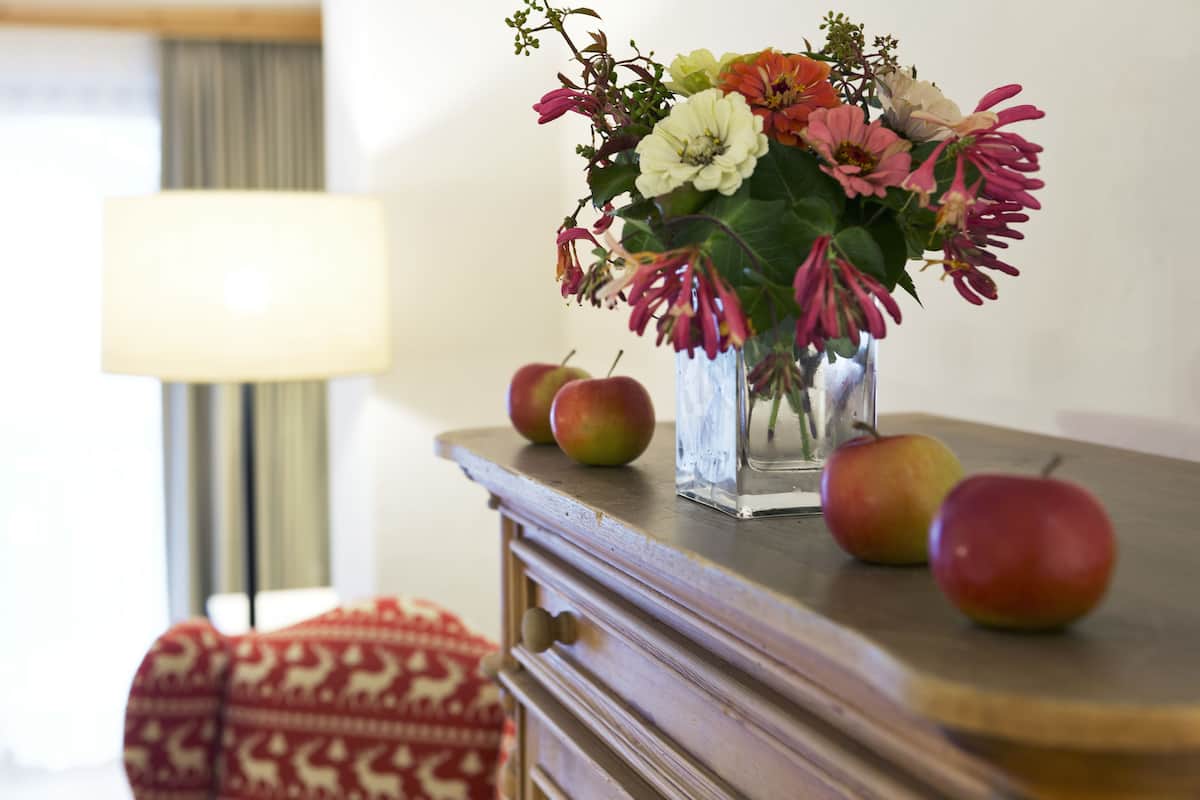 Une table avec un vase de fleurs et des pommes.