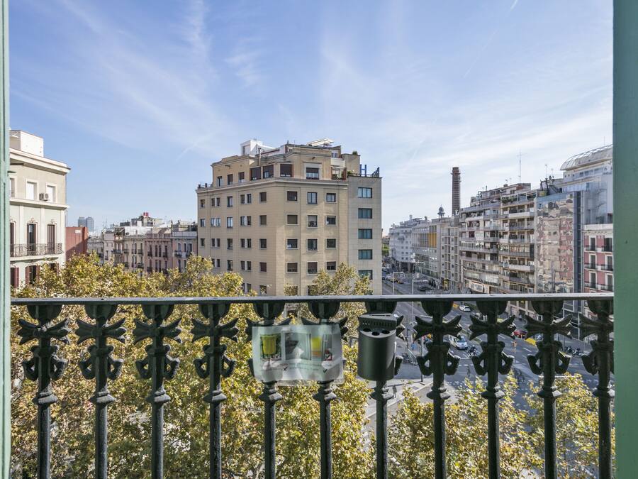 A balcony with a view of a cityscape, featuring a mix of residential and commercial buildings.