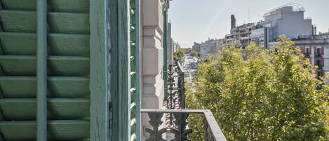 A balcony with a view of a cityscape, including buildings and a tree.