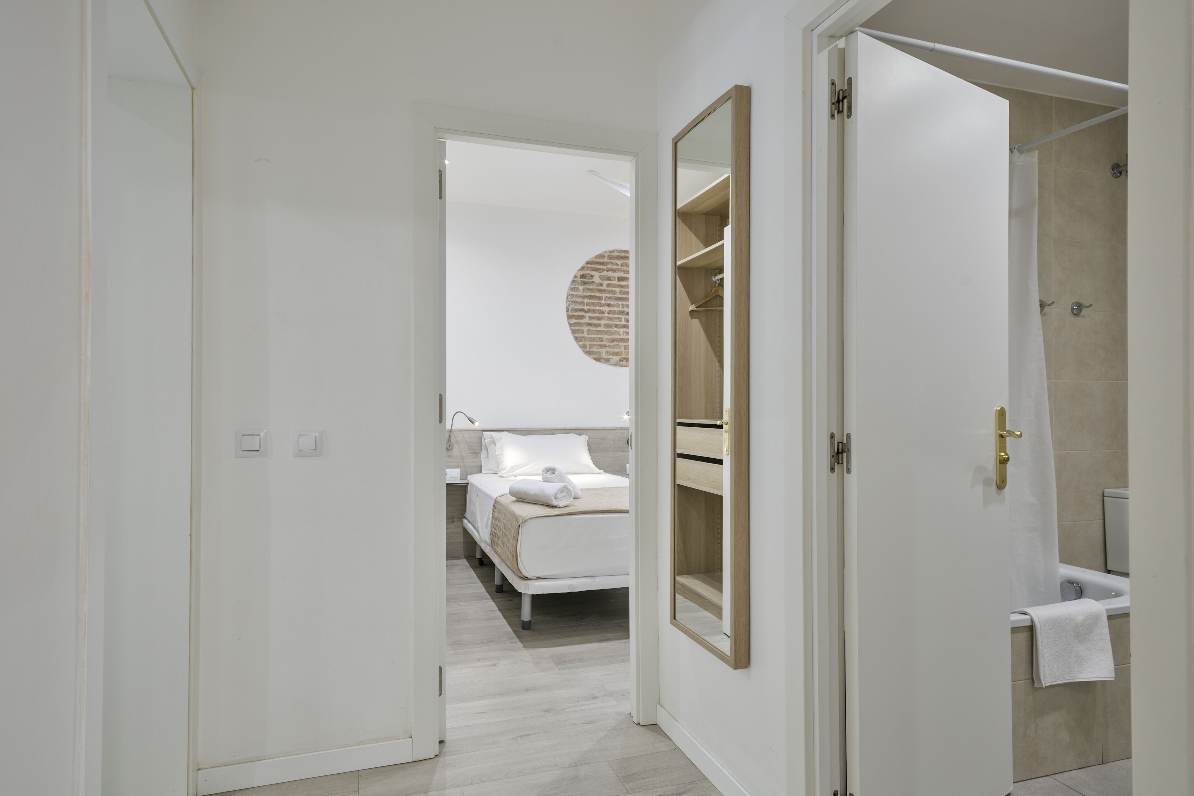 A modern hotel room with a bed, a bathroom with a bathtub, and a large mirror.