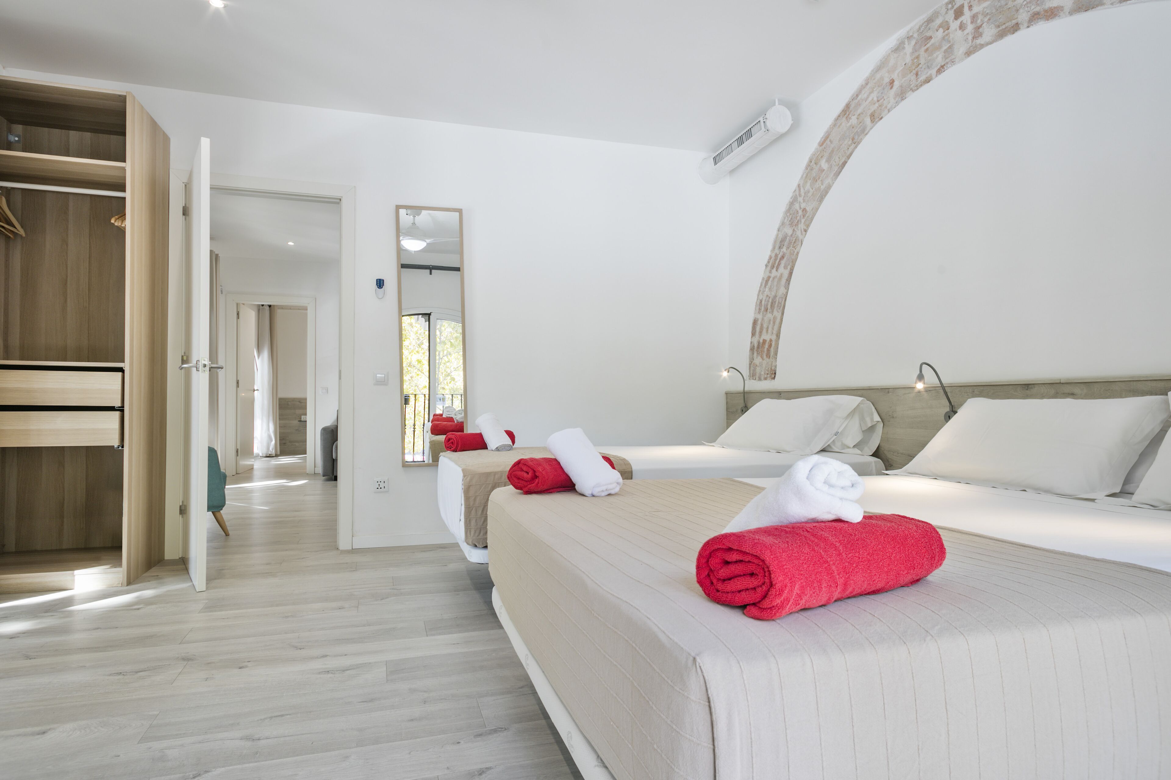 A hotel room with two beds, a wooden wardrobe, and a mirror.