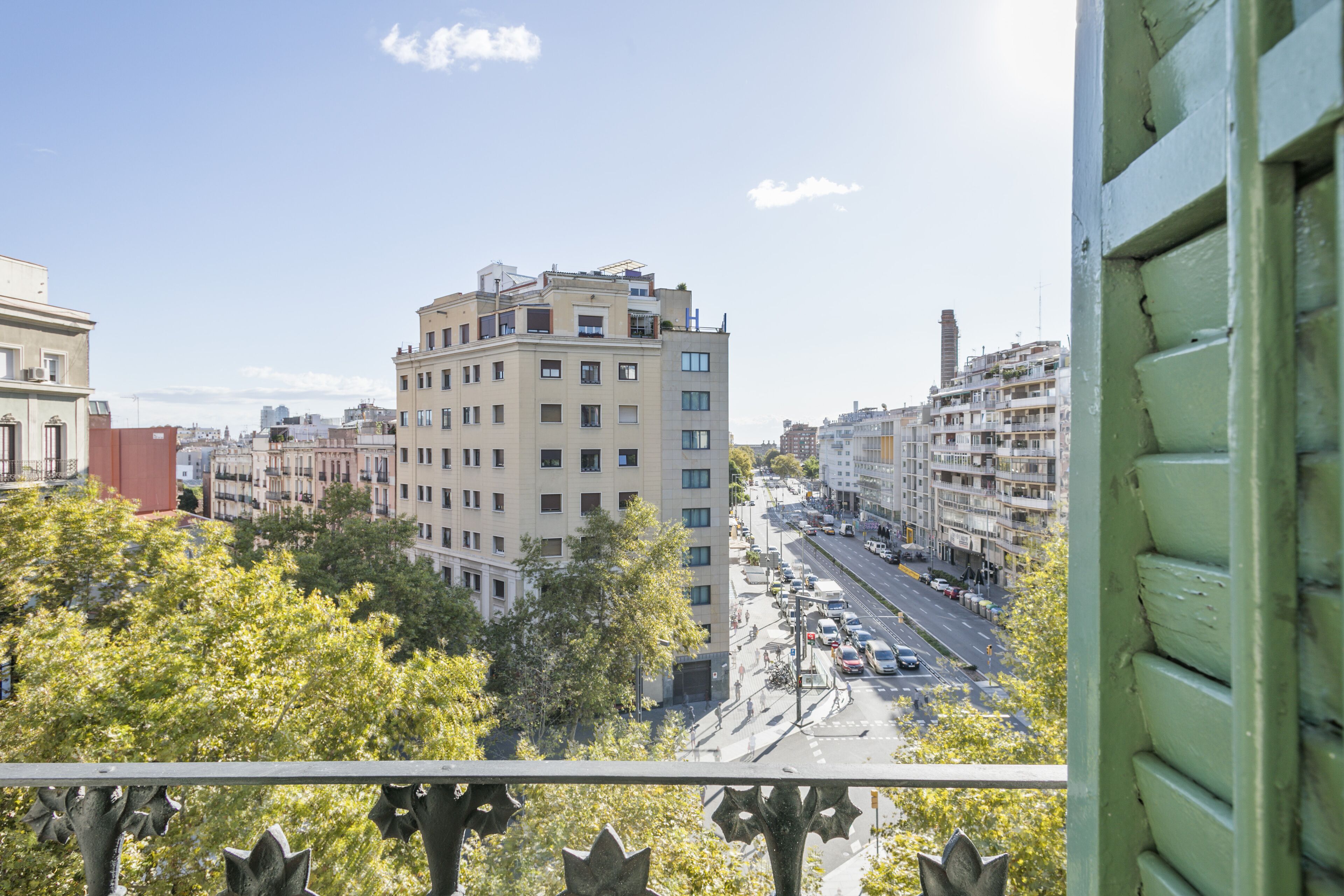 A cityscape with a prominent multi-story building, a busy street, and surrounding trees.