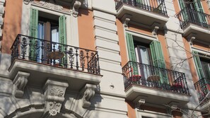 Een gevel met sierlijke balkons, groene luiken en klassieke architectuurelementen.