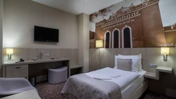 Una habitación de hotel con una cama, un escritorio, un televisor y un mural en la pared.