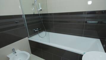 Une salle de bain moderne équipée d’une baignoire, d’un bidet et d’un lavabo.