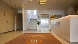 A hotel reception area with a staircase, a reception desk, and a welcome mat. - Košice Hotel (Kosice)