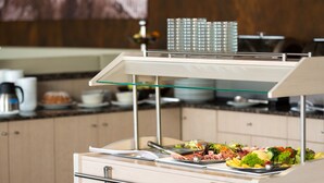 A buffet setup with various food items and a coffee machine in the background. - Košice Hotel (Kosice)