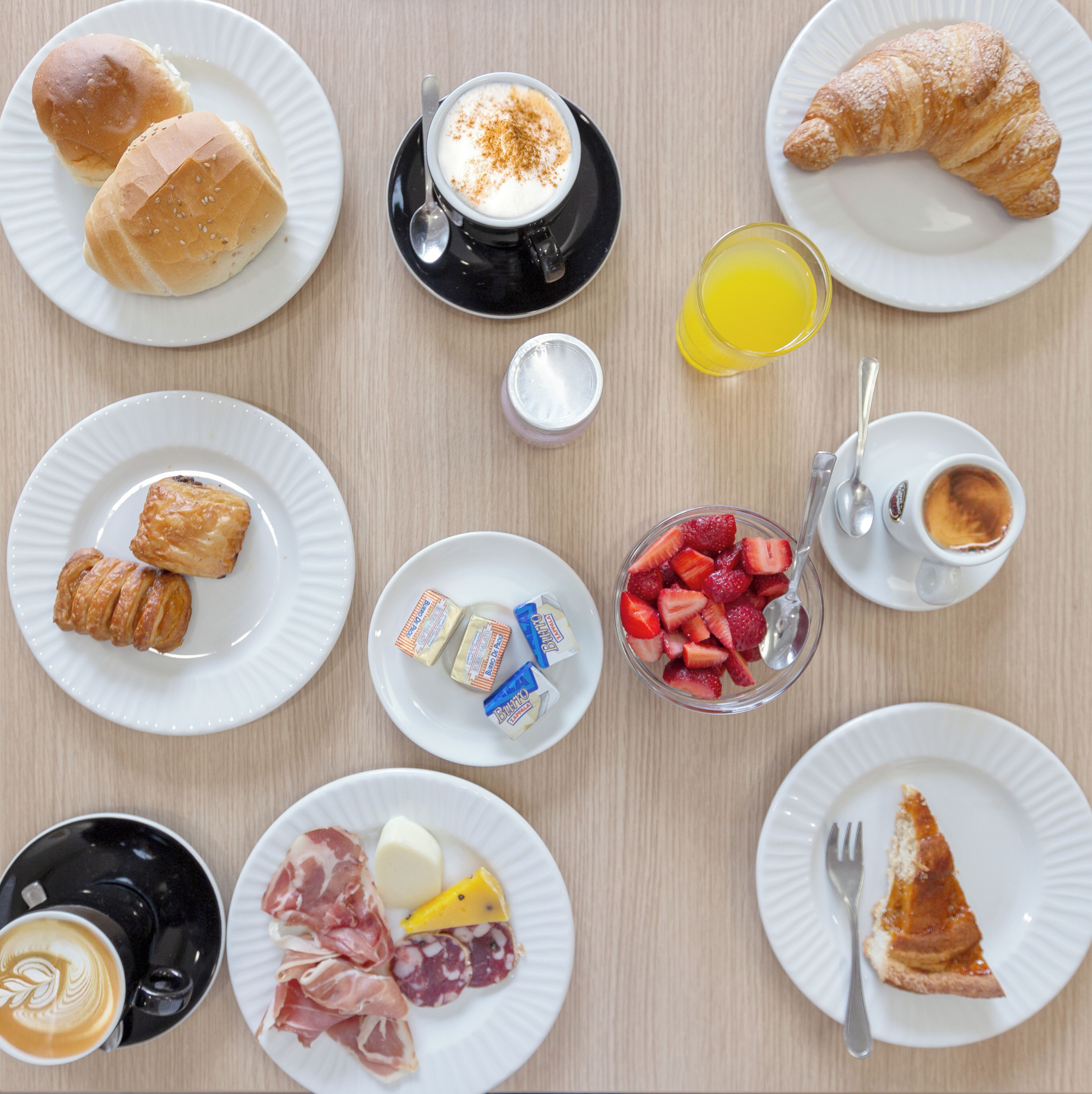A breakfast setting with various food items and drinks on plates.