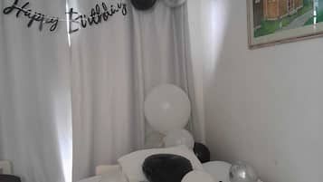 Un dormitorio con una cama, un cartel de 'Feliz Cumpleaños' y globos.