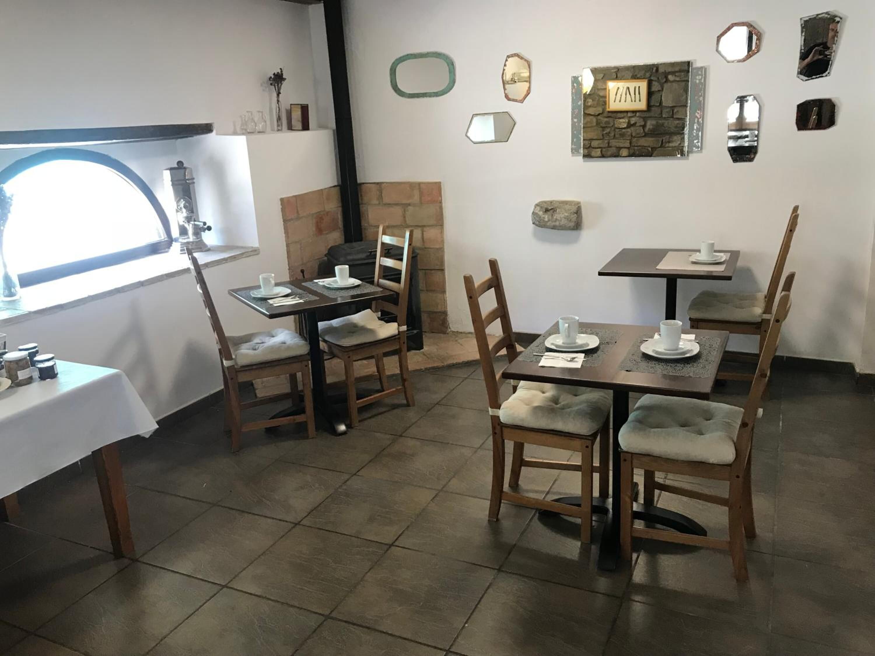 A dining area with two tables and chairs, a fireplace, and various wall decorations.
