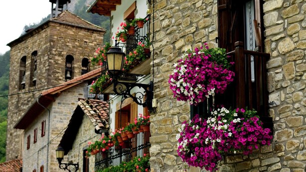 A stone building with a bell tower, flower boxes on the windows, and a traditional tiled roof. - Casa Rural Argonz Etxea (Urzainqui)