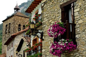 A stone building with a bell tower, flower boxes on the windows, and a traditional tiled roof. - Casa Rural Argonz Etxea (Urzainqui)